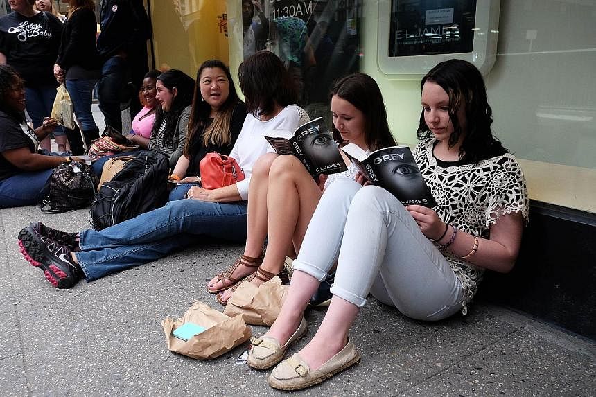 E.L. James' (left) new book, Grey, being read by fans outside a New York book store.