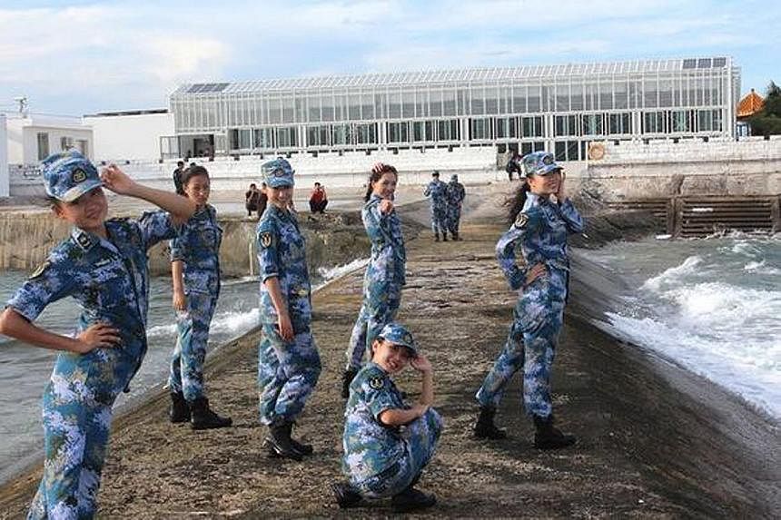 One of the 17 photos shows female troops posing on a breakwater with a greenhouse in the background.