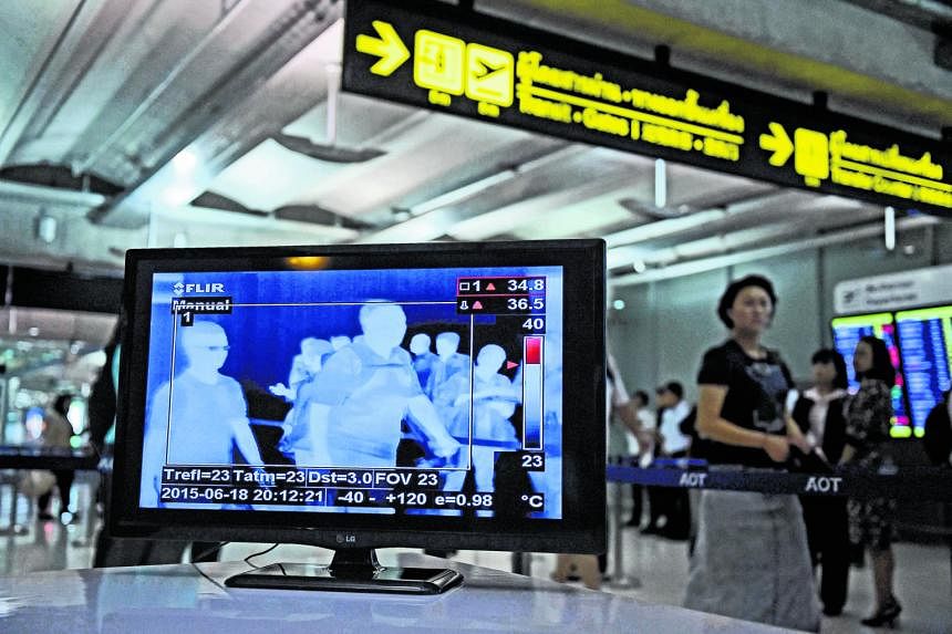 Travellers arriving at Bangkok's Suvarnabhumi Airport being scanned for fever (above), while (left) a woman dons a mask at Bamrasnaradura Infectious Diseases Institute where the Mers patient is being isolated.