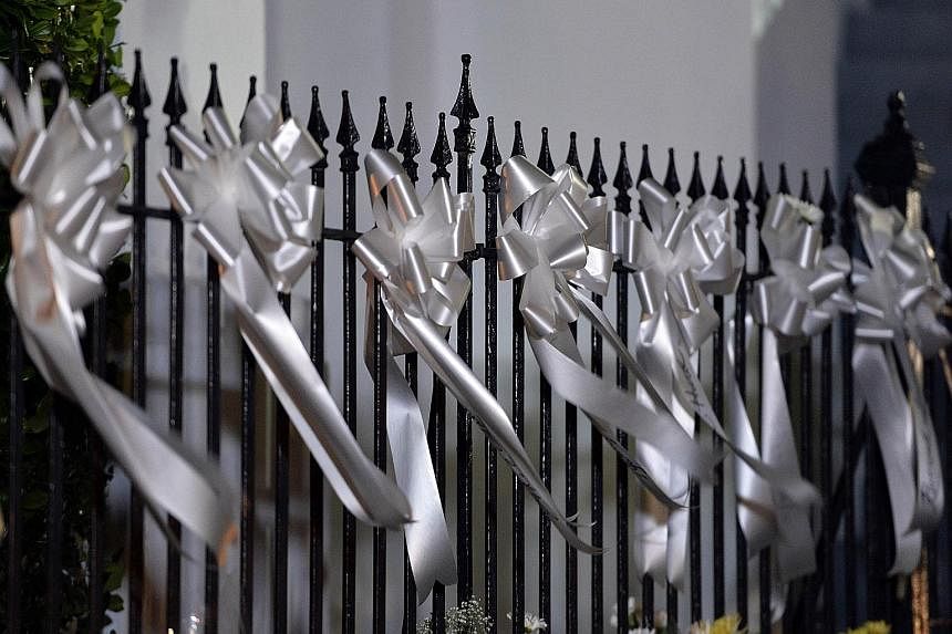 White ribbons commemorating victims of the hate crime on a railing outside the Emanuel African Methodist Episcopal Church in Charleston, South Carolina. Police leading suspected killer Dylann Roof into the courthouse in Shelby, North Carolina on Thur