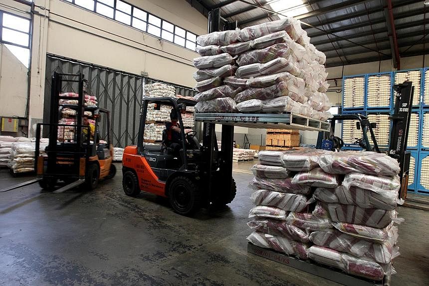 A worker stacking rice at a warehouse in Pasir Panjang. Major rice importers here, like NTUC FairPrice, stockpile at least three months' supply of rice to ensure they can cope with fluctuations in stock from overseas. Supermarket chains and rice impo