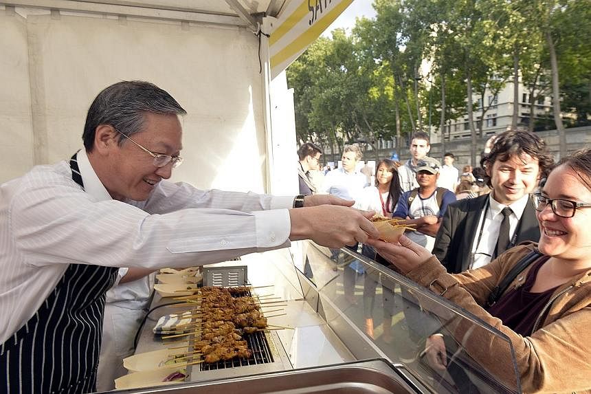 Minister of State Sam Tan (left) was on hand on Thursday to serve satay to visitors at Saveurs de Singapour sur les Berges de Seine in Paris. Temasek Polytechnic students whipped up popular Singaporean dishes such as bak kut teh and chendol for visit