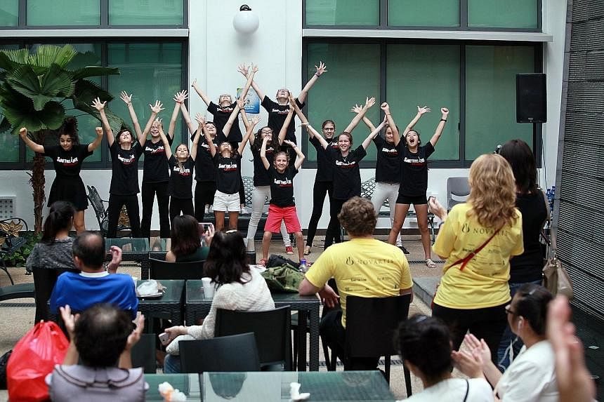 Young members of the Sing'theatre Academy (above) putting up a song-and-dance performance yesterday. Meanwhile, patient Seah Mui Huay (below), 79, sang along as actor/DJ Hossan Leong Leong performed the Teresa Teng classic, The Moon Represents My Hea