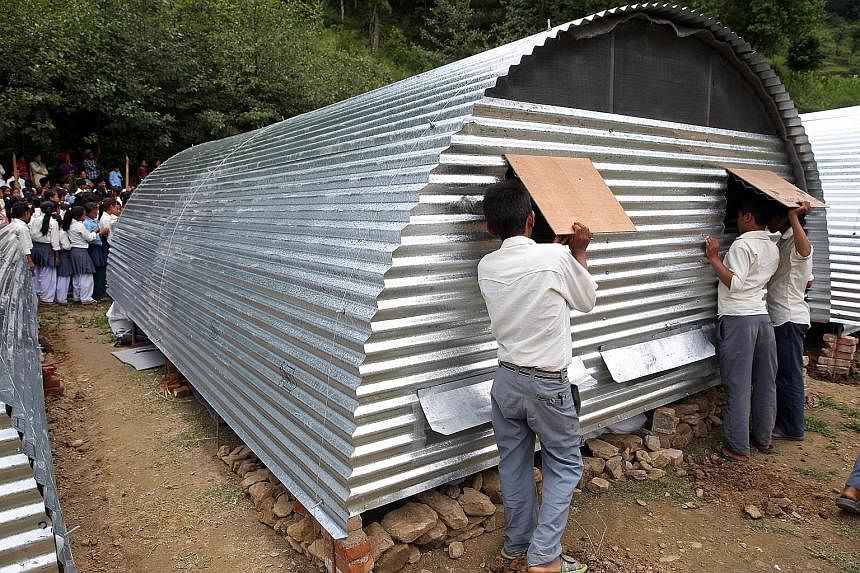 Mercy Relief is using $220,000 of Singapore public donations to build shelters (above) to withstand rain until October, when it can start work on permanent homes. For now, many quake survivors are housed in tents (below).