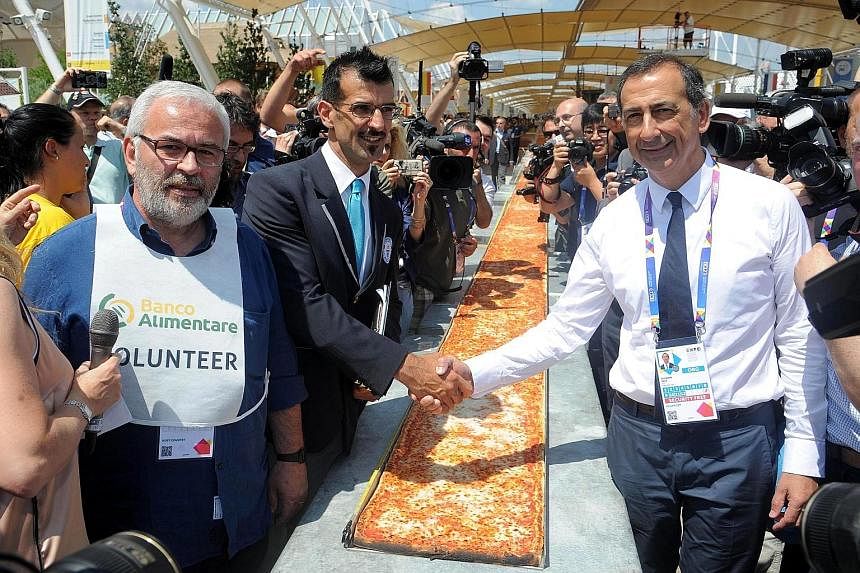 Guinness World Records judge Lorenzo Veltri (centre) congratulates expo commissioner Giuseppe Sala at Milan's 2015 Expo in Italy on Saturday. A total of 80 chefs from all over Italy took part in the creation of the world's longest pizza, snatching th