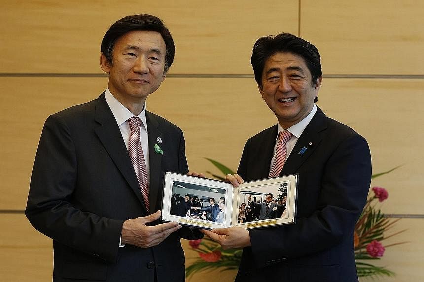 South Korean Foreign Minister Yun Byung Se (left) presenting Japanese PM Shinzo Abe with photos of Mr Abe's father, former foreign minister Shintaro Abe, taken in 1984, at their talks in Tokyo yesterday.