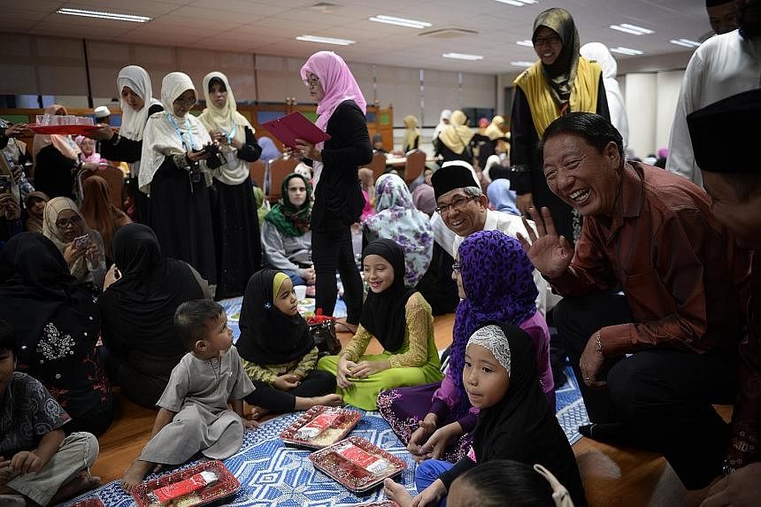 Deputy Prime Minister Teo Chee Hean (right) and Minister-in-charge of Muslim Affairs Yaacob Ibrahim (second from right) chatting with young Muslims breaking fast at Mujahidin Mosque in Commonwealth yesterday.