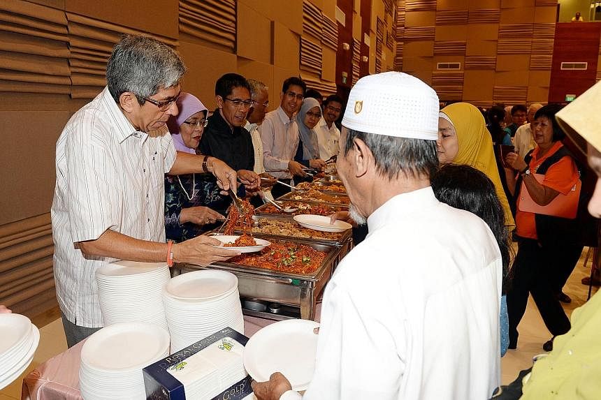 Helping to serve low-income workers and their families at a breaking-of-fast session are (from left) Dr Yaacob Ibrahim, Madam Halimah Yacob, Dr Maliki Osman, Mr Hawazi Daipi, Associate Professor Muhammad Faishal Ibrahim, Dr Intan Azura Mokhtar and Mr