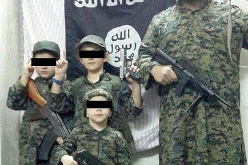 ISIS fighter Khaled Sharrouf, who is believed to have been killed, posing with boys said to be his sons in front of the militant group's flag. His mother-in-law is pleading for his wife and children to be allowed to return home.