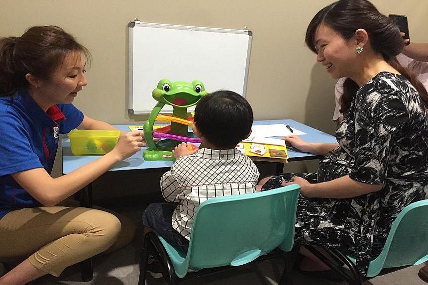 Four-year-old Koo Wen Rui working with his therapist at Thye Hua Kwan Moral Charities' new centre for special needs children yesterday, as Marine Parade GRC MP Tin Pei Ling observes.