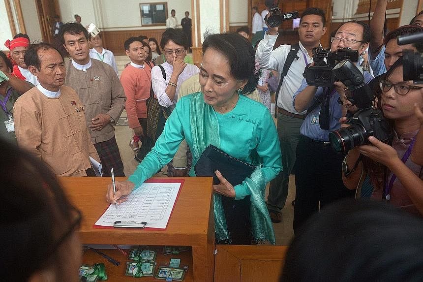 Ms Suu Kyi registering before attending a Parliament session yesterday. She urged people not to "lose hope" after the failure to amend the Constitution, saying the opposition would not "back down" from elections.