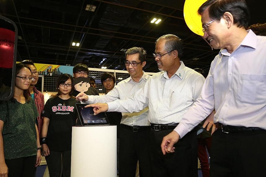 (From right) Mr Chan Lee Mun, principal and chief executive officer of Nanyang Polytechnic, Mr Masagos and Mr Ng Ser Song, director of Central Narcotics Bureau, checking out the mobile game application Nelzon.