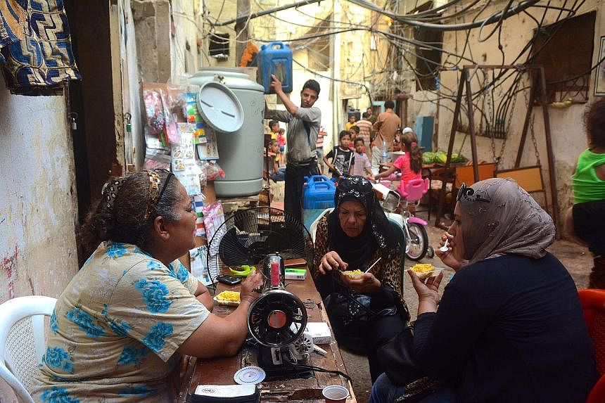 A seamstress chatting with her friends outside her home in a narrow lane, which also doubles as a workspace.