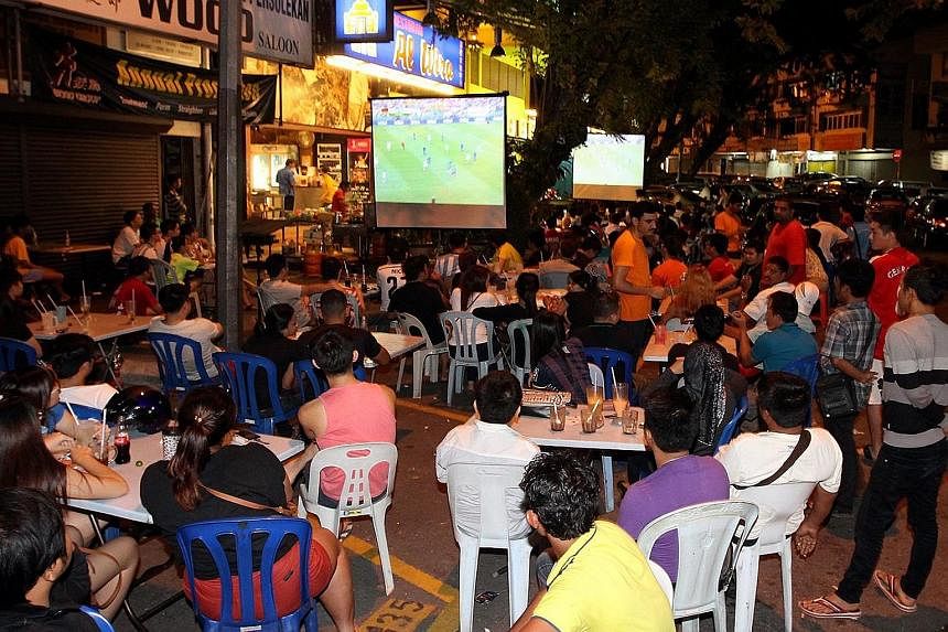 Football fans watching a televised match at an eatery in Kuala Lumpur. A minister has said that the proposal to end operating hours at midnight follows complaints about 24-hour restaurants and hawker centres.