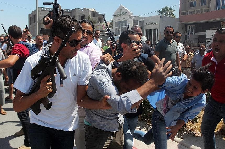 Members of the Tunisian security forces escorting a man suspected of being involved in opening fire at a beach in the tourist town of Sousse yesterday, killing at least 27 people. British holidaymakers said tourists ran from the beach when they reali