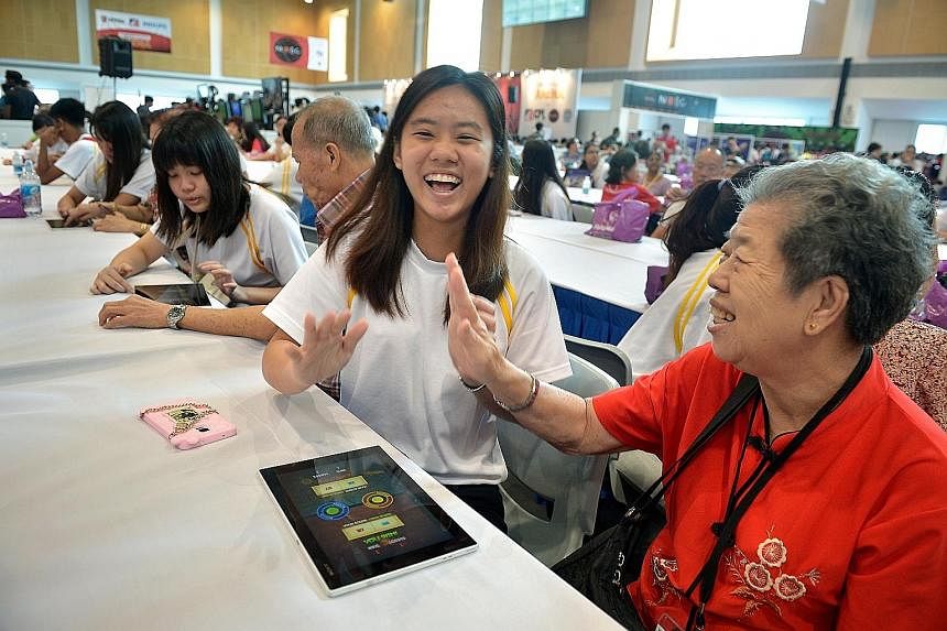 ITE student Celine Si, 19, playing Fruit Ninja with retiree Ng Geok Heok, 70, who was among 50 senior citizens invited to the Institute of Technical Education College Central yesterday.