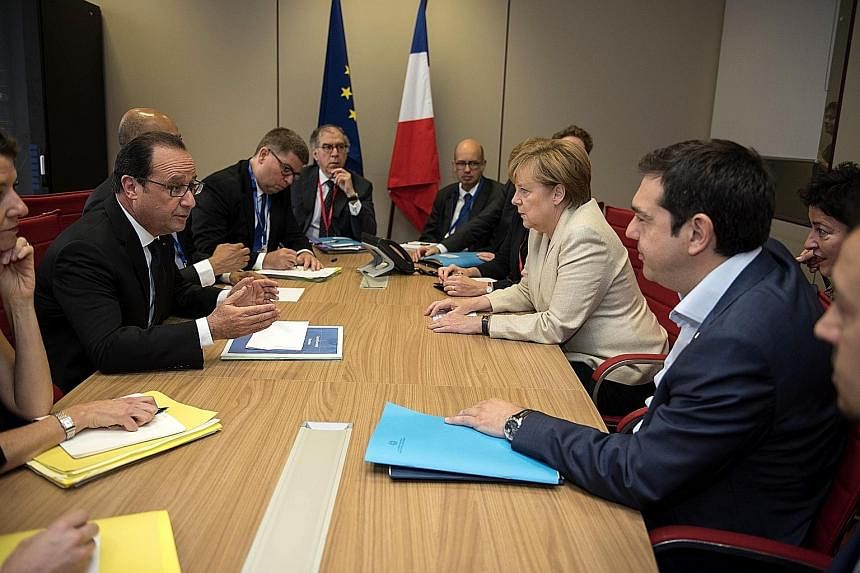 Mr Francois Hollande (left) in talks with Dr Angela Merkel (second from right) and Mr Alexis Tsipras (right) during a Brussels summit yesterday. Mr Hollande and Dr Merkel said today's emergency meeting of euro-zone finance ministers would be decisive