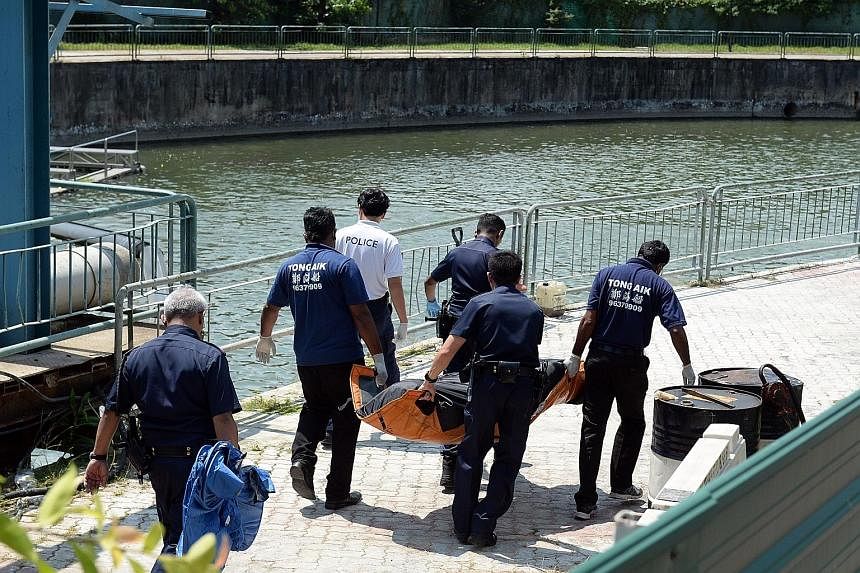 Police officers and workers from an undertaker carrying the body yesterday. The body was found floating in the water at a quieter part of Rochor Canal.