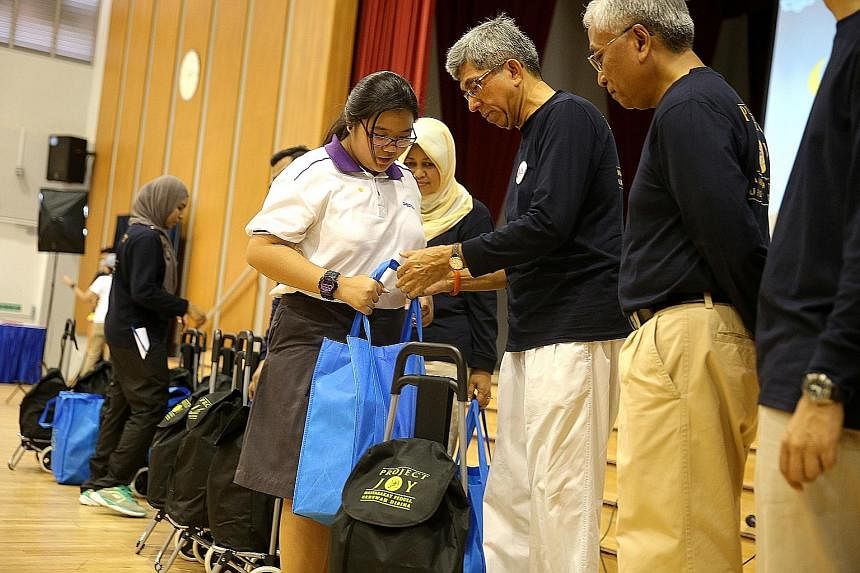 ABOVE: A Spectra Secondary School student from a low-income family receiving a bag of groceries from Minister-in- charge of Muslim Affairs Yaacob Ibrahim, as Senior Parliamentary Secretary for Education and Manpower Hawazi Daipi looks on. LEFT: Assoc