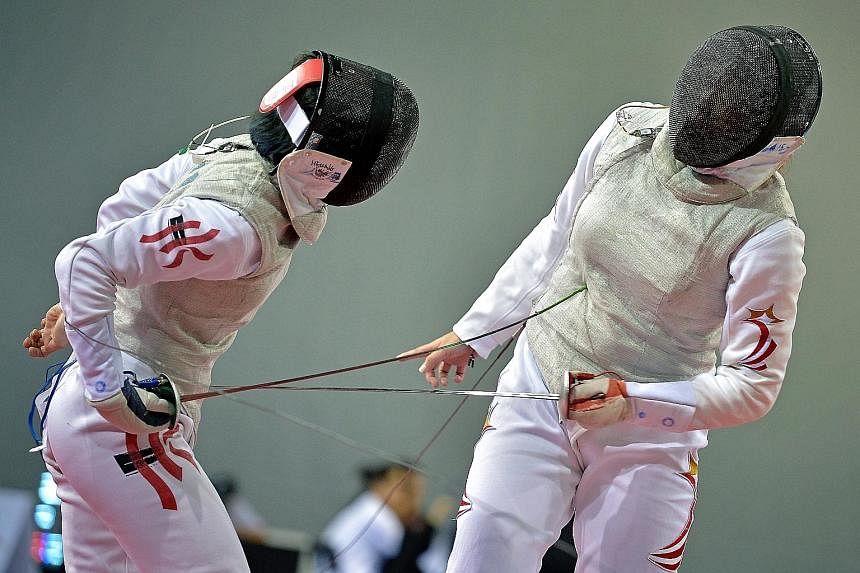 Singapore's Wang Wenying (right) losing a point to Hong Kong's Lin Po Heung during their last-16 encounter in the women's foil yesterday.
