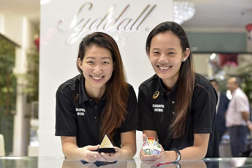 Goal shooter Charmaine Soh (left) and national netball captain Micky Lin with their one-carat diamond earrings (in box) and SEA Games gold medal. The earrings' design consists of a hoop and ball. They also received $500 in cash each.