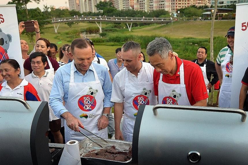 Prime Minister Lee Hsien Loong and his Australian counterpart Tony Abbott (left) grilling some steaks at Bishan Park yesterday with Australian celebrity chef Dallas Cuddy (centre). This was one of 50 barbecues held simultaneously around Singapore to celeb