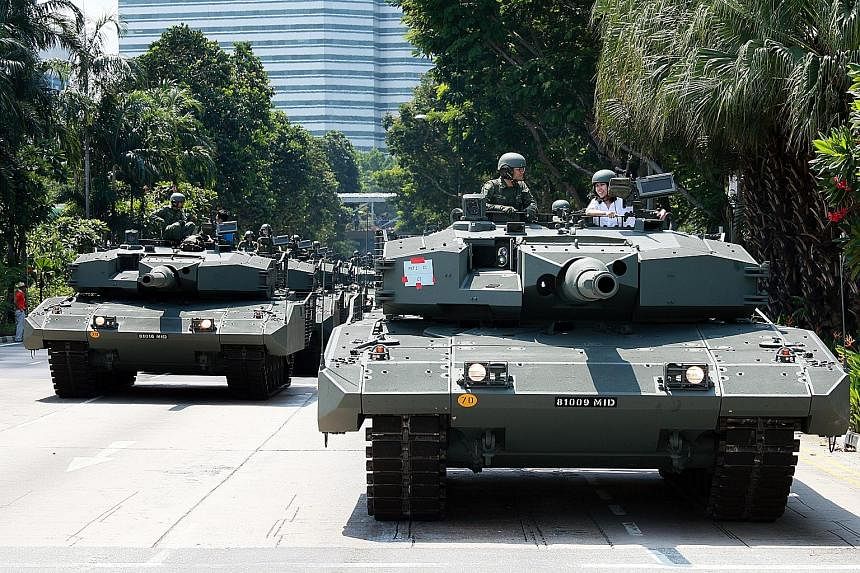 Reporter Lim Yi Han (in white in right tank) talking to tank commander Jon Lee aboard the Leopard 2SG Main Battle Tank. The column had stopped on Nicoll Highway to wait for the go-ahead while en route to the Padang.