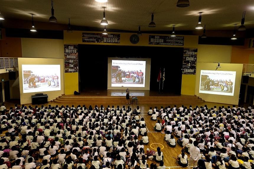 Tanjong Katong Primary School principal Caroline Wu addressing the pupils yesterday during the morning assembly, where she called on them to be strong and move on. At the entrance to the school, sunflowers and balloons (below) greeted the pupils as t