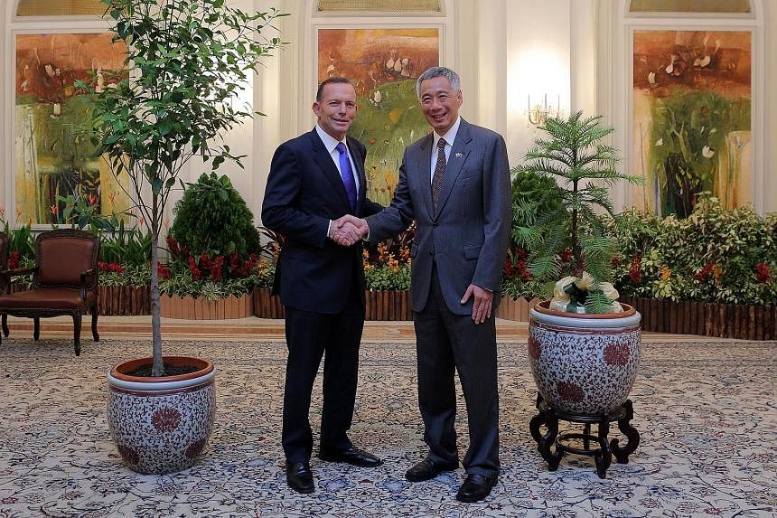 (Above) Australian Prime Minister Tony Abbott calling on President Tony Tan Keng Yam at the Istana yesterday during his official visit to Singapore. (Left) Mr Abbott and PM Lee Hsien Loong with the gifts, a Wollemi pine (beside Mr Lee) from Australia