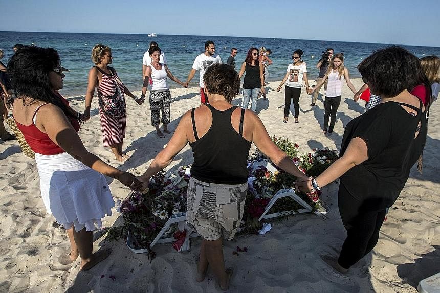 People praying around bouquets of flowers laid in memory of the victims at the Imperial Marhaba resort. Last Friday, a Tunisian student disguised as a tourist opened fire on holidaymakers killing 39 and wounding 38. The Tunisian government said armed