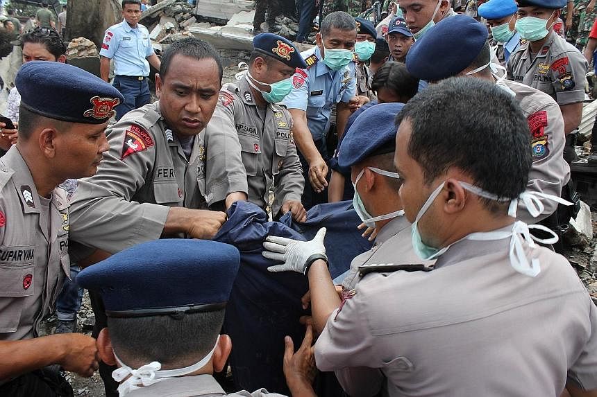 Indonesian rescue workers retrieving a body from the scene of the air crash in Medan yesterday. All 113 people on board the military plane perished in the crash.