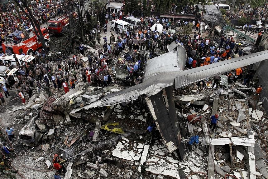 Security personnel and rescue teams examining the wreckage of an Indonesian military C-130B Hercules transport plane, which crashed into a residential area in Medan yesterday. An Air Force spokesman said it was unclear what caused the crash.
