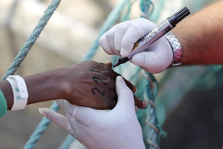 A staff member writing an identification number on a rescued migrant's hand as he disembarks from the Norwegian vessel Siem Pilot at Catania's harbour in Italy on Tuesday.
