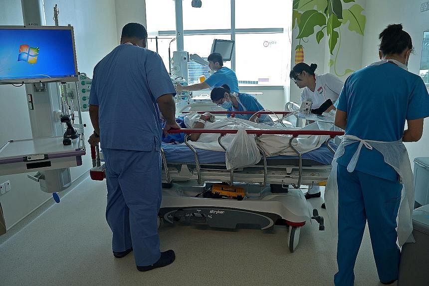 Doctors (above) from the Intensive Care Medicine Team yesterday watching the hospital's first patient, who was moved from the accident and emergency department, as he undergoes a CT scan before he is wheeled to the high-dependency ward (below). Mr Li