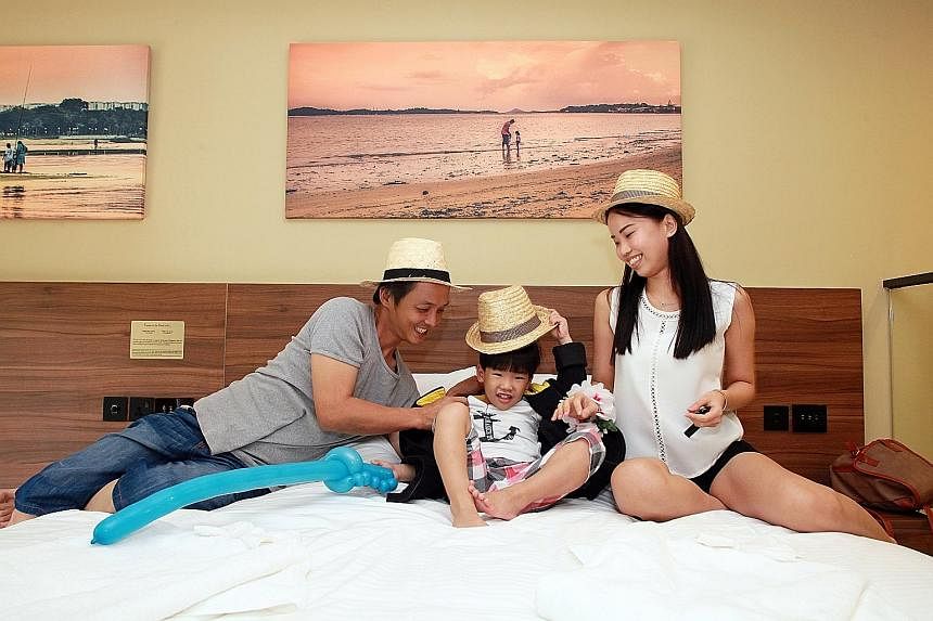 Mr Andy Ng, his wife Felicia and their younger son Junior, in their duplex room at the D'Resort at Downtown East yesterday. Mr Ng and his family were the first guests at the newly built NTUC resort.