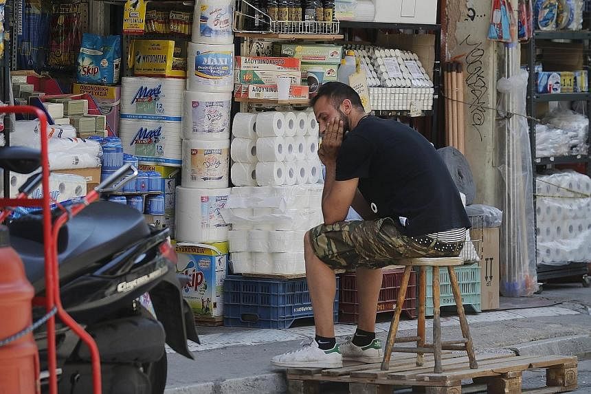 A shopkeeper waiting for customers outside his shop in Athens. According to the National Confederation of Hellenic Commerce, the economic uncertainty has meant an average of 59 businesses closing down every 24 hours in recent months.