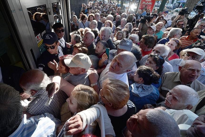 Pensioners crowding outside a bank in Athens yesterday, after the government temporarily reopened almost 1,000 bank branches to allow pensioners without ATM cards to withdraw €120 to last the rest of the week. About 57,000 Greek retirees will not r