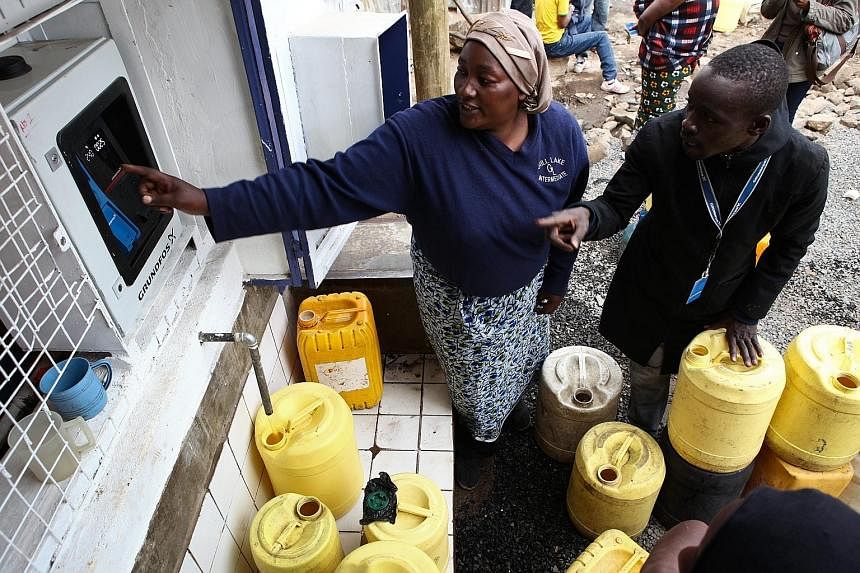 A resident of the Mathare slums in Nairobi (left) getting some help in buying clean water from an ATM-style water dispenser last week. The clean water from such dispensers is cheaper than what other water vendors used to charge for water that was oft
