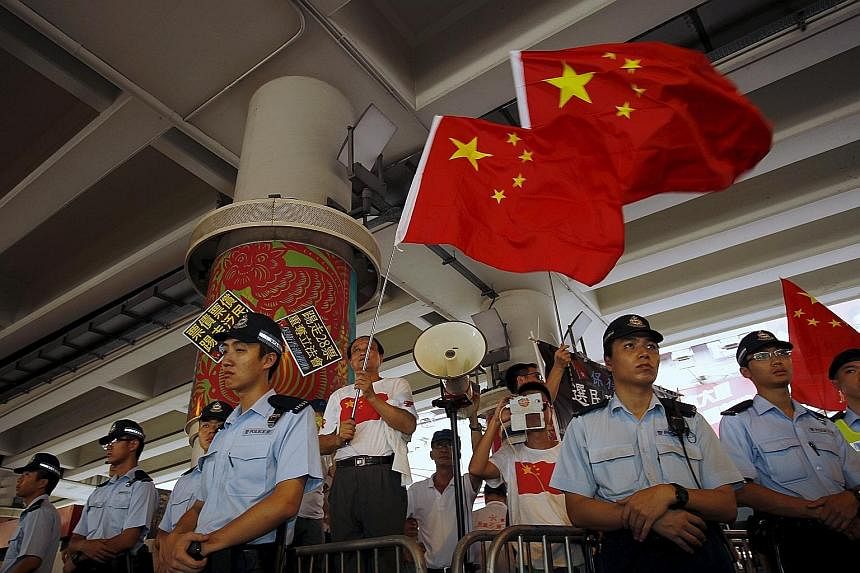 Protesters carrying Hong Kong colonial flags and anti-China placards during a march in the city yesterday. Pro-China supporters (above) were also out in force yesterday, the anniversary of Hong Kong's handover to Chinese sovereignty