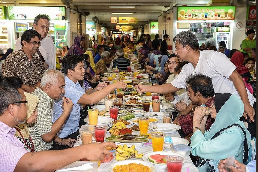 Minister for Social and Family Development Tan Chuan-Jin reaching for dates offered by Mr Razak Ismail of Hajjah Mona Nasi Padang at the breaking-of-fast session held at Geylang Serai market yesterday.