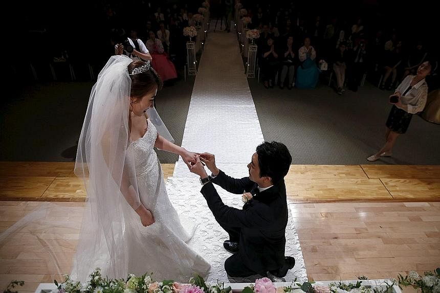 I do... want a modest wedding ceremony. Here, a couple tie the knot at a budget wedding, held at the National Library of Korea in Seoul. To boost marriage rates, the government is renting out public buildings cheaply.