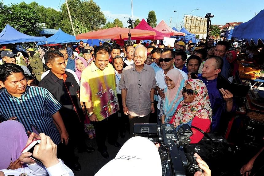 Malaysian PM Najib Razak (centre) at a Ramadan bazaar in Semenyih in Selangor yesterday. The Wall Street Journal reported on Friday that he had received up to $940 million in personal accounts in AmBank between March 2013 and February this year. Mala