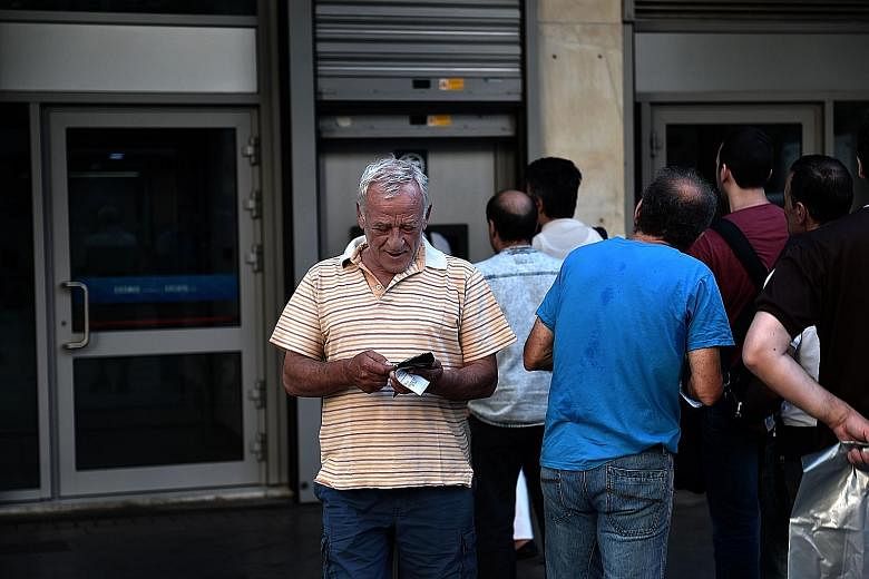 A queue at an ATM in Athens yesterday. Banks will stay shut for two more days, after the European Central Bank denied a request for more emergency funding.