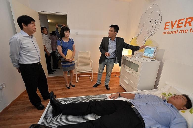 National Development Minister Khaw Boon Wan (left) and HDB CEO Cheong Koon Hean watching a demonstration of a device that can monitor an elderly resident in bed.