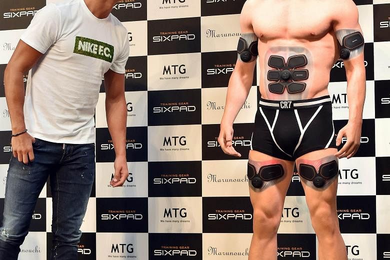 A bemused Cristiano Ronaldo inspects his look-alike figure made by a 3D printer, which is equipped with the Training Gear Sixpad designed by the Portuguese star.