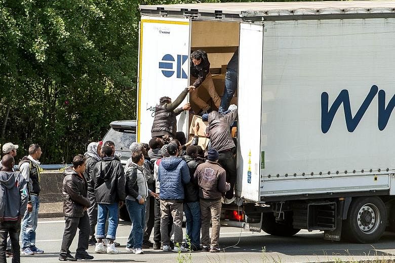 Migrants trying to climb aboard a lorry on a highway leading to the Eurotunnel, during a road blockade in Calais late last month.