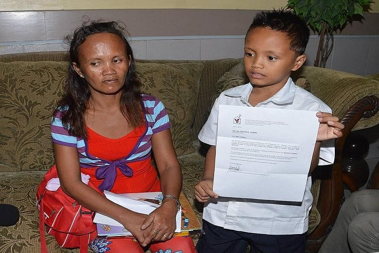 Daniel, pictured with his mother, Ms Christina Espinosa, has been overwhelmed with aid after a photo of him (right) studying on the pavement by the light of a McDonald's outlet went viral on the Internet.