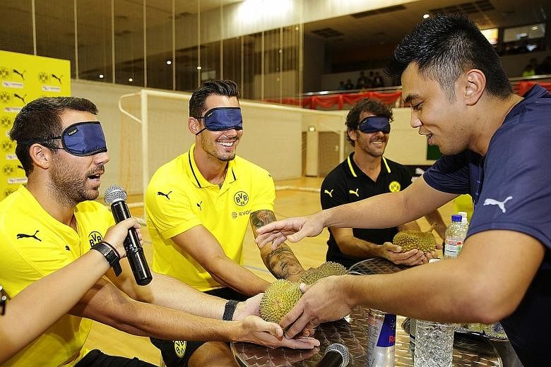 Above: Time to meet the king of fruits at Nanyang Polytechnic, as Dortmund's (from left) Gonzalo Castro, Roman Burki and club legend Karl-Heinz Riedle have their first feel of durian blindfolded. Right: Over at 313@Somerset, Dortmund players (from le