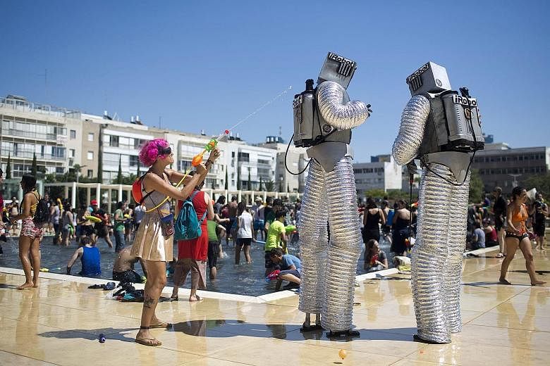 Israelis don costumes to spray water on one another during the Tel Aviv Water War on Friday. The annual mass "water fight" is in its 11th edition.
