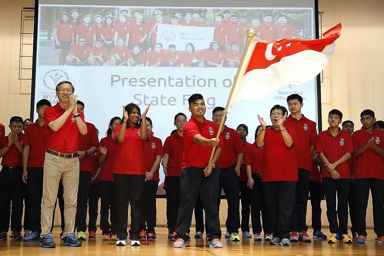 Table-tennis player Nor Safik Nor Mohd Bahtiar waves the national flag at a send-off ceremony attended by Minister of State Sam Tan.
